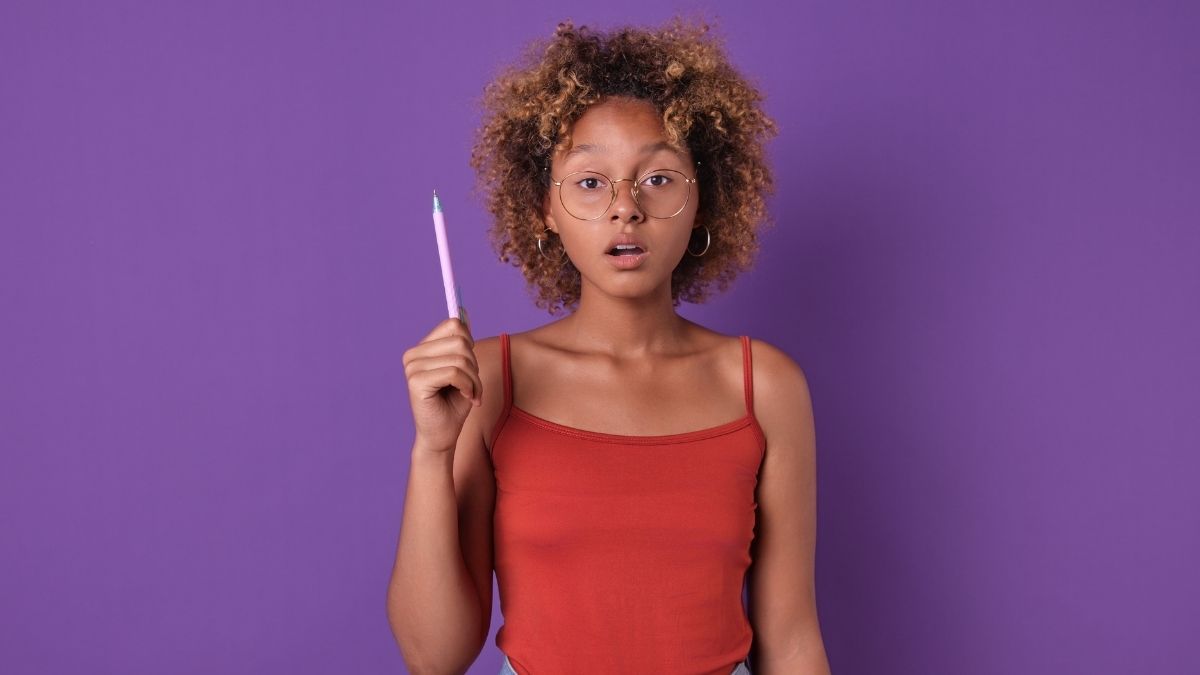 Inquisitive young woman with glasses holding a pencil — symbolizing questions to ask a mortgage broker.